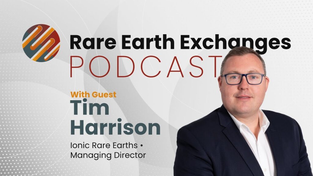 s1-e35-ionic-rare-earths-recycli man in a suit and glasses standing in front of a sign