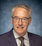 man in a suit and tie posing for a picture, highlighting the importance of critical minerals in modern industries
